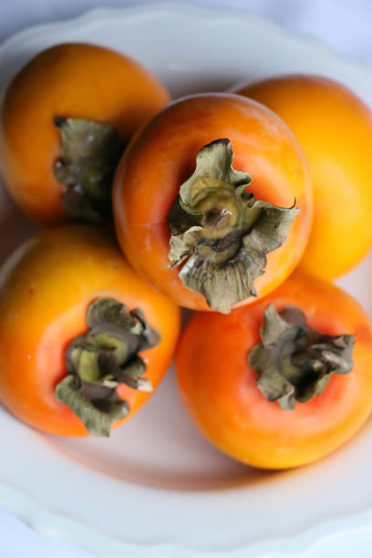 istock Fresh Ripe Persimmons on a White Classic Design Plate, Paradise Palms, Close-up 1307803139