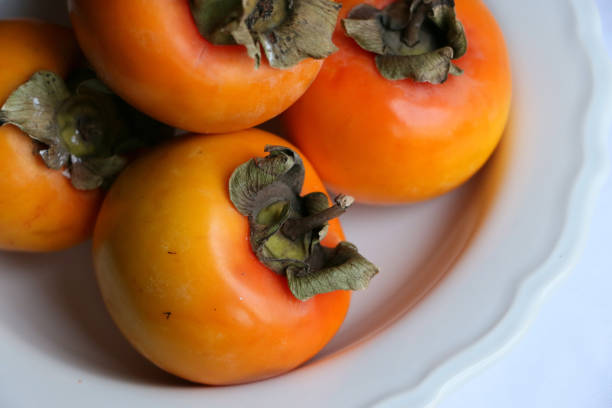 istock Fresh Ripe Persimmons on a White Classic Design Plate, Paradise Palms, Close-up 1307803226
