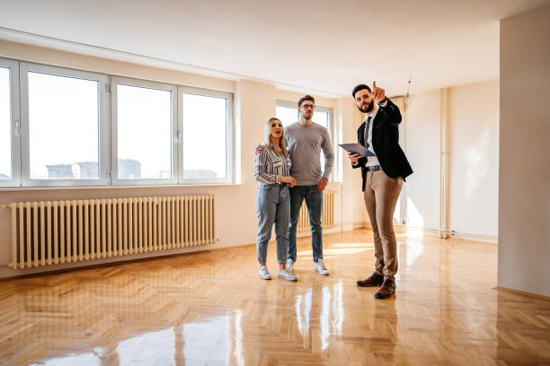 агент по недвижимости показывает квартиру на продажу молодой паре - house agent стоковые фото и изображения