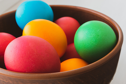 Easter eggs in brown bowl. Happy Easter holiday. Colorful painted eggs. Bright boiled eggs. Easter traditional decoration. Christian holiday. Easter celebration. Spring holidays concept.
