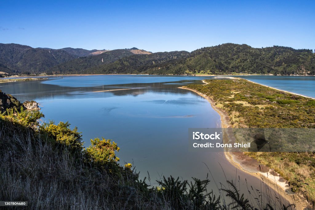 Wainui Bay and Takapou Bay from Coast Walkway Looking down from the inland track on the Abel Tasman Coast Walkway onto Wainui Bay and Takapou Bay and the long sandspit between the two bays under a clear blue sky. Abel Tasman National Park Stock Photo