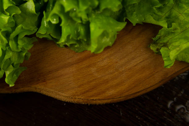 Lettuce leaves lie on the board, top view. Lettuce leaves on a wooden textured background. Background with fresh vegetables.