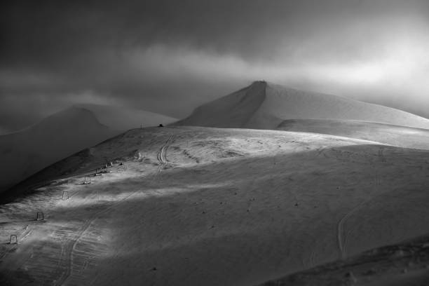 istock Grayscale. Snow covered mountain slope in last evening sunlight. Magnificent windy dusk on picturesque alpine ski resort, Dragobrat, Ukraine, Carpathian Mountains. 1307805490