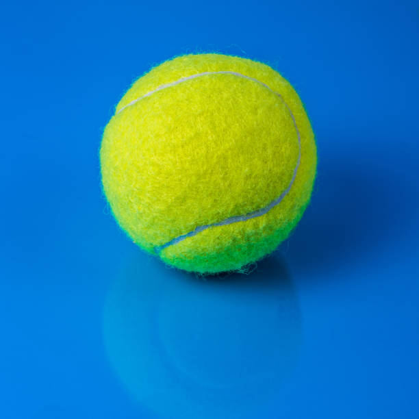 istock Tennis ball on blue background with reflection 1307806595