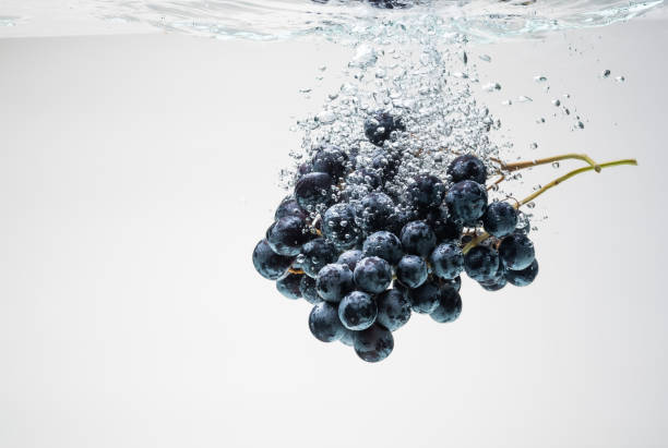 istock Bunch of blue grapes sinking underwater with splash. 1307806686