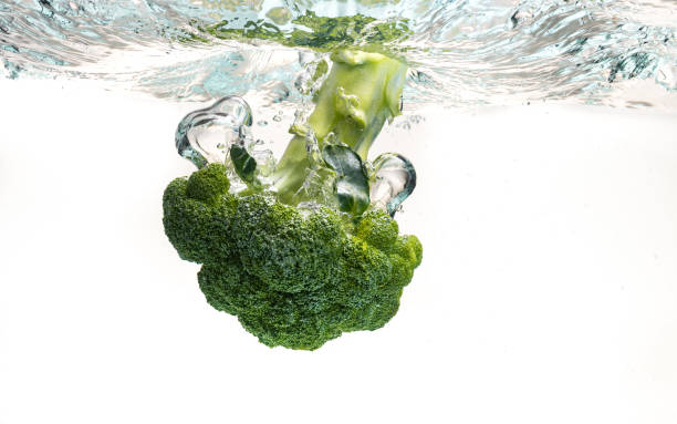 istock Close-up of broccoli splash into water isolated on white. 1307806694