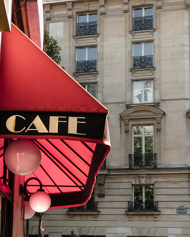 Classical red cafe sign in the outside central Parisian street and a typical building in the background. 11 District.