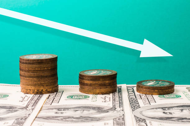 istock Coins, dollars and arrow pointing down, recession concept. 1307807930