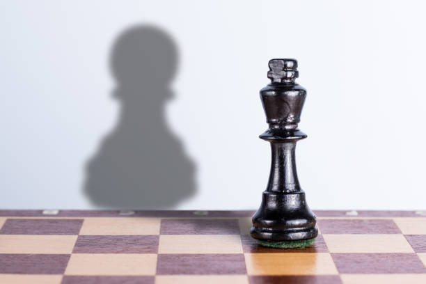 istock Black chess king with pawn shadow. Exaggeration of possibilities concept. 1307809186