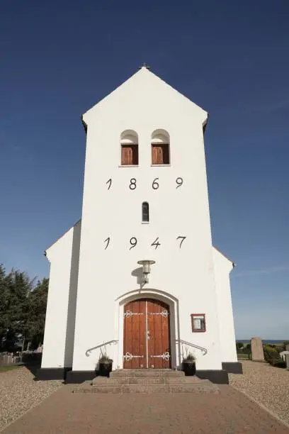 Haurvig Kirke and its cemetery with sea in background and blue sky