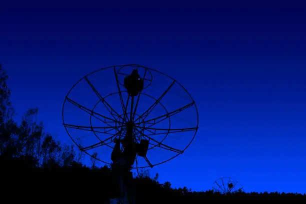 radiotelescopes silhouettes under dark blue sky background