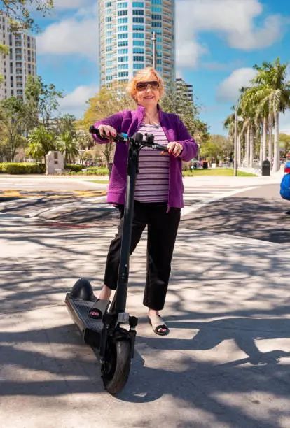 Happy senior woman with ride share scooter in Florida