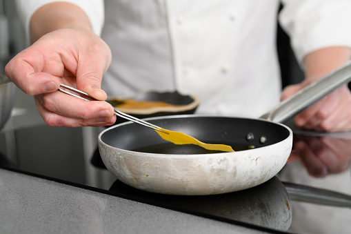 Close-up view of male chef cooking on frying pan. High quality photo