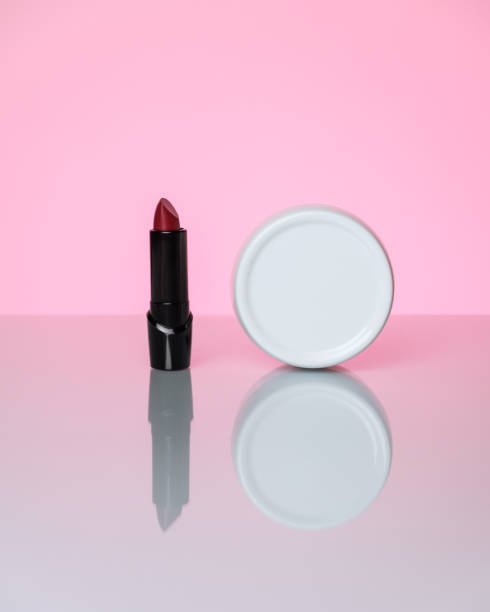 istock Hand cream and red lipstick on a pink background with reflection. 1307816061