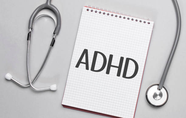 On a beige background, a stethoscope and a white notepad with the inscription ADHD.Medical concept stock photo
