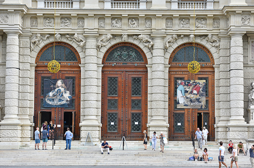 In front of the entrance gates of the Kunsthistorisches Museum KHM in Vienna some visitors are waiting for admission