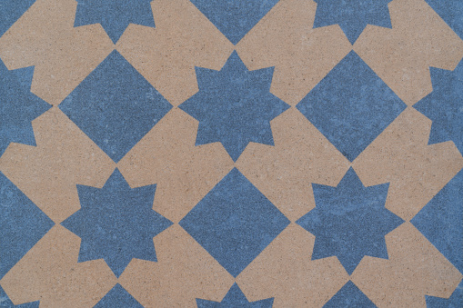 An illustration of blue diamond-shaped forms and polygonal stars on a light brown background