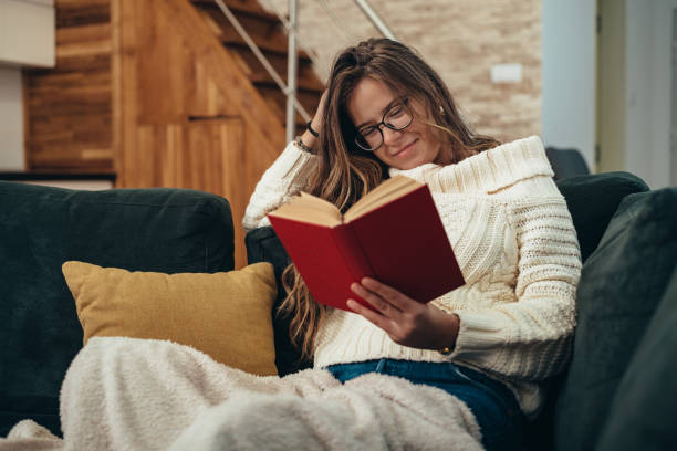 istock Woman with glasses reading a book at home 1307831452
