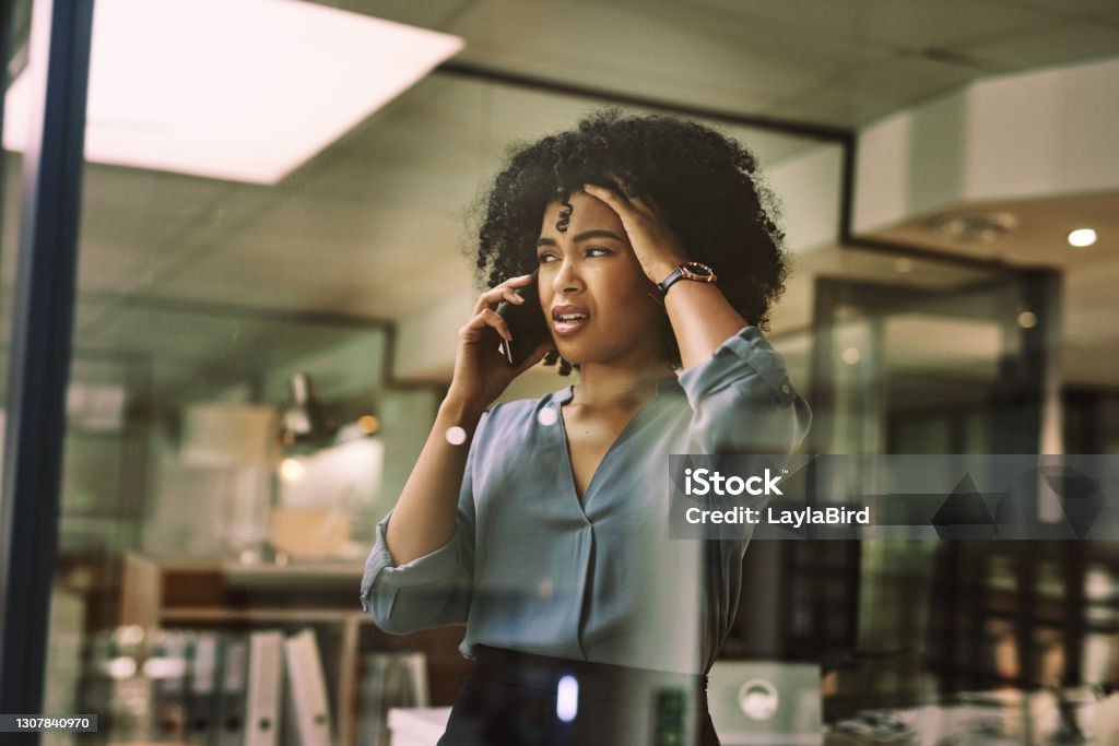 Nothing is going right tonight Shot of a young businesswoman looking stressed while using a smartphone during a late night at work Using Phone Stock Photo