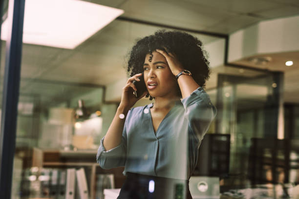 Nothing is going right tonight Shot of a young businesswoman looking stressed while using a smartphone during a late night at work displeased stock pictures, royalty-free photos & images