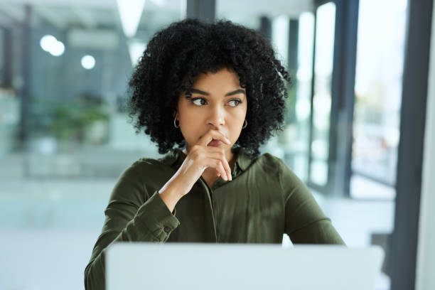 You can take a fall and still find a way Shot of a young businesswoman looking thoughtful while using a laptop in a modern office bluff stock pictures, royalty-free photos & images