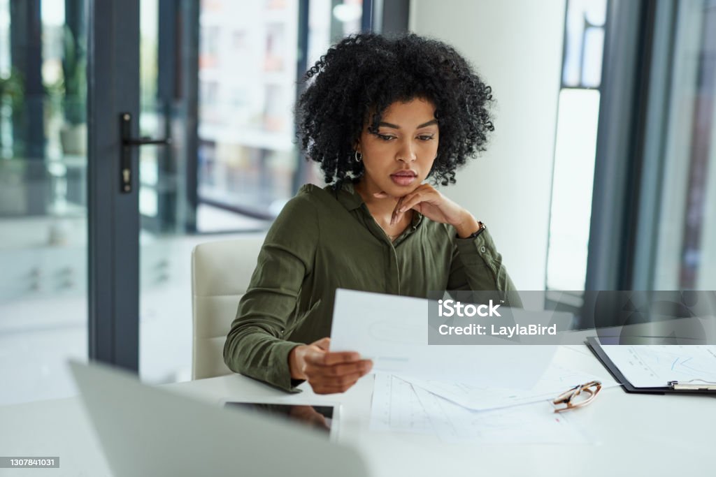 The best number cruncher in the business Shot of a young businesswoman going over paperwork in a modern office Bookkeeping Stock Photo
