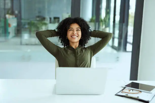 Shot of a young businesswoman taking a break at her desk in a modern office