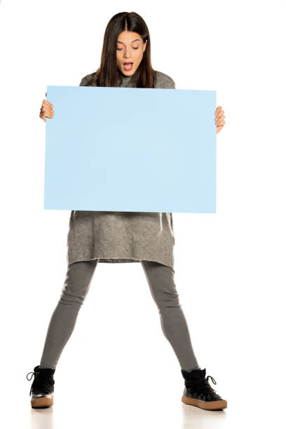 istock young beautiful excited woman holding a blue empty board 1307843601