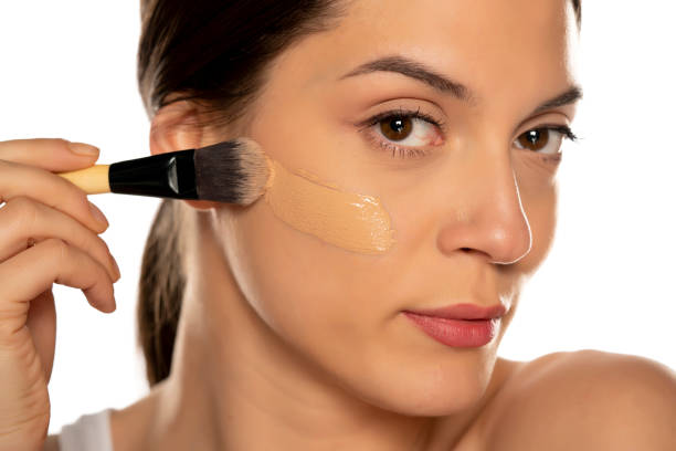istock Young woman applying liquid foundation with the brush 1307844550