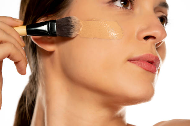 istock Young woman applying liquid foundation with the brush 1307844552