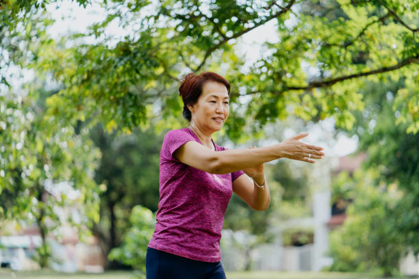 istock Senior Asian woman practicing Tai Chi at public park 1307846189