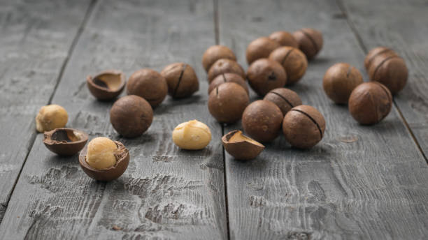 istock Scattered macadamia nuts on a black wooden table. 1307851017