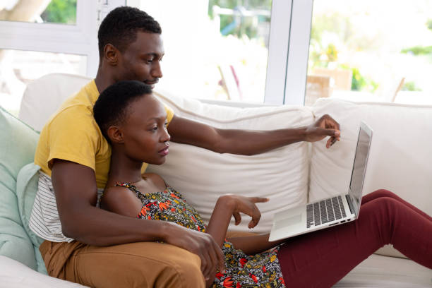 istock African american couple sitting on sofa using laptop computer and smiling 1307852174