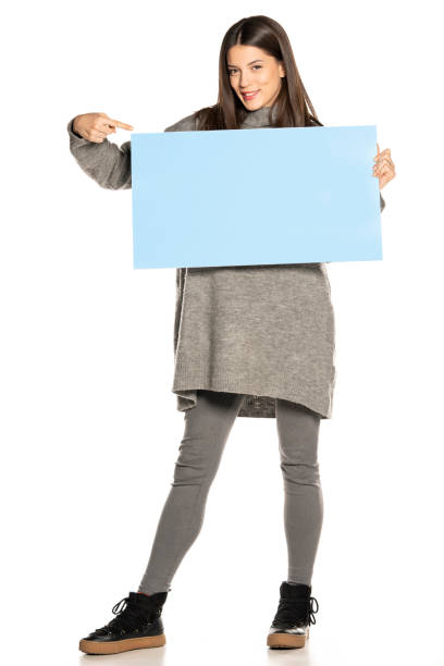 istock young beautiful happy woman holding a blue empty board on white background 1307852294