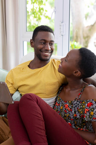 istock African american couple sitting on sofa using tablet and smiling 1307852818