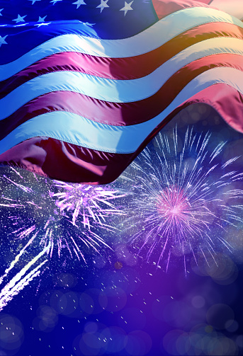 close up waving American flag and celebration fireworks over night sky