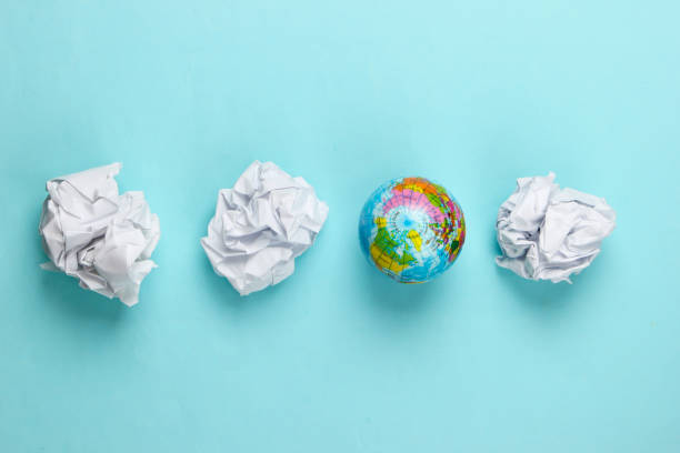 istock Globe with crumpled paper balls on a blue background. Top view. Concept art. 1307858627