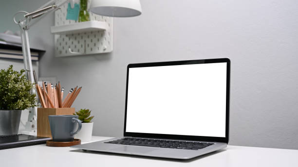 istock Computer laptop with blank screen an office supplies on white table. 1307861382
