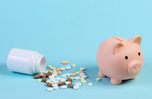 Piggy bank with bottle of pills on blue background