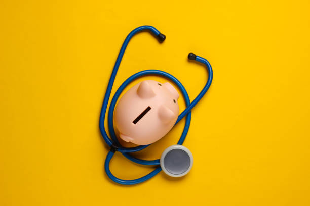 Medicine still life. Piggy bank with stethoscope on yellow background. Top view Medicine still life. Piggy bank with stethoscope on yellow background. Top view operating budget stock pictures, royalty-free photos & images