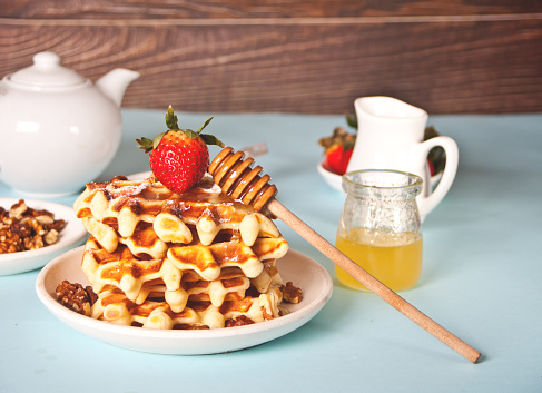 Freshly homemade baked waffles with strawberries and honey