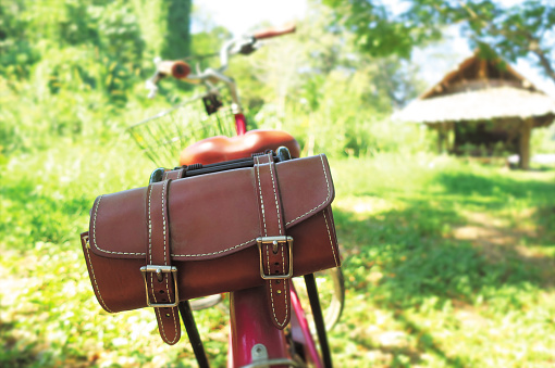 Brown leather bag on rear of the bicycle that parking at asia farm