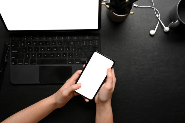istock Female hands using smartphone on dark creative workspace with laptop and supplies 1307875202