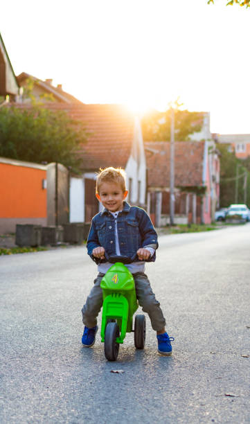 Boy's ride around the neighborhood Small boy is having fun outdoors riding his motorcycle. motorcycle 4 wheels stock pictures, royalty-free photos & images