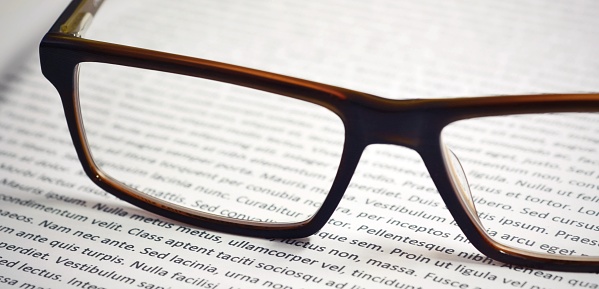 Closeup of eyeglasses on paper sheet with lorem ipsum text.