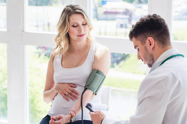 medico che controlla la pressione sanguigna di una donna incinta - patient blood pressure gauge doctor male foto e immagini stock