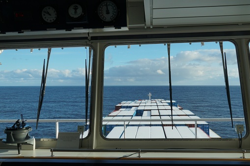 View form the window  of the navigational bridge of the container vessel on the containers covered with snow underway through Pacific ocean during calm sea in winter season.