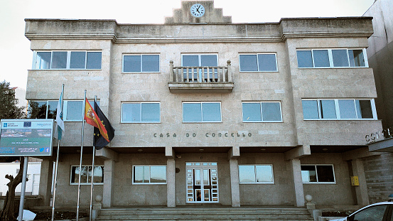 Laxe, Spain- Mars 15, 2021: Town hall in Laxe, close-up of modern facade, clock, windows, balcony and flags and staircase.Town square . Costa da morte, A Coruña province, Galicia, Spain.