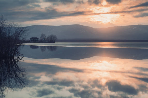 Beautiful sunset on the shore of lake in early spring. Beautiful sunset on the shore of lake in early spring. Trees are reflected in the calm water surface south ural stock pictures, royalty-free photos & images