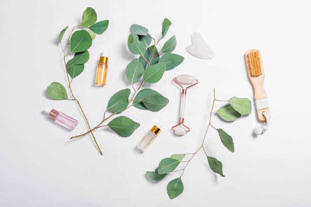 Facial rollers, massage brush, essential oils or cosmetic serums with natural eucalyptus leaves on light background. Beauty products, massage tools, facial skin care, spa beauty treatment concept rodillos faciales, cepillo de masaje, aceites esenciales o sueros cosméticos con hojas naturales de eucalipto sobre fondo claro. productos de belleza, herramientas de masaje, cuidado facial de la piel, concepto de tratamiento de belleza spa.